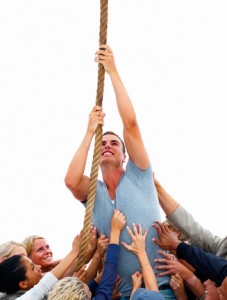 Group of people pulling a man climbing up a rope isolated on whi